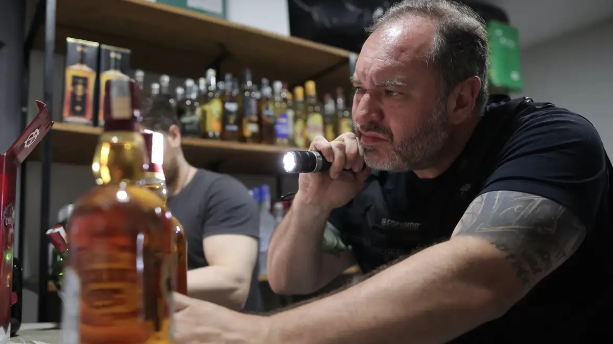Metanol Policial aponta lanterna para uma bebida alcoólica