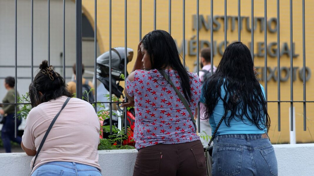 Mulheres aguardam diante do portão do Instituto Médico Legal