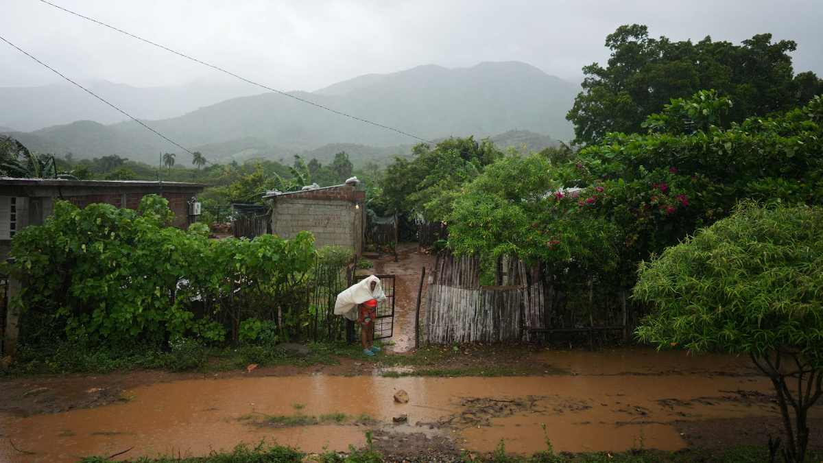 Mulher tenta se proteger do furacão em frente a uma rua alagada