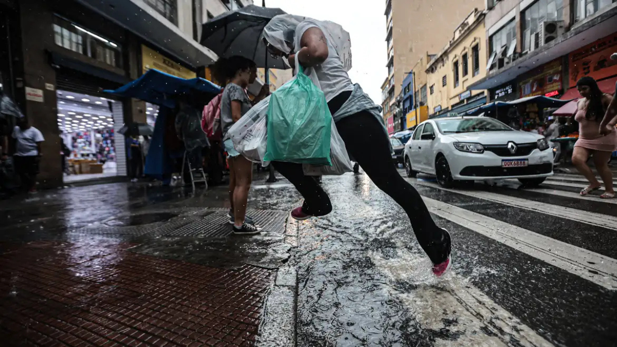Chuva Homem pula uma poça d'água ao atravessar a rua