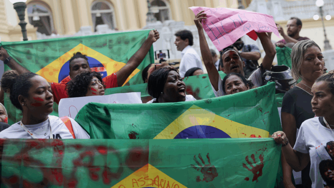 Fórum Pessoas erguem bandeiras do Brasil com marcas de mãos pintadas de vermelho em protesto