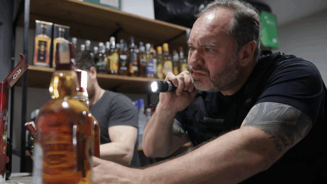 Bebida Adulterada homem analisa garrafa de bebida adulterada