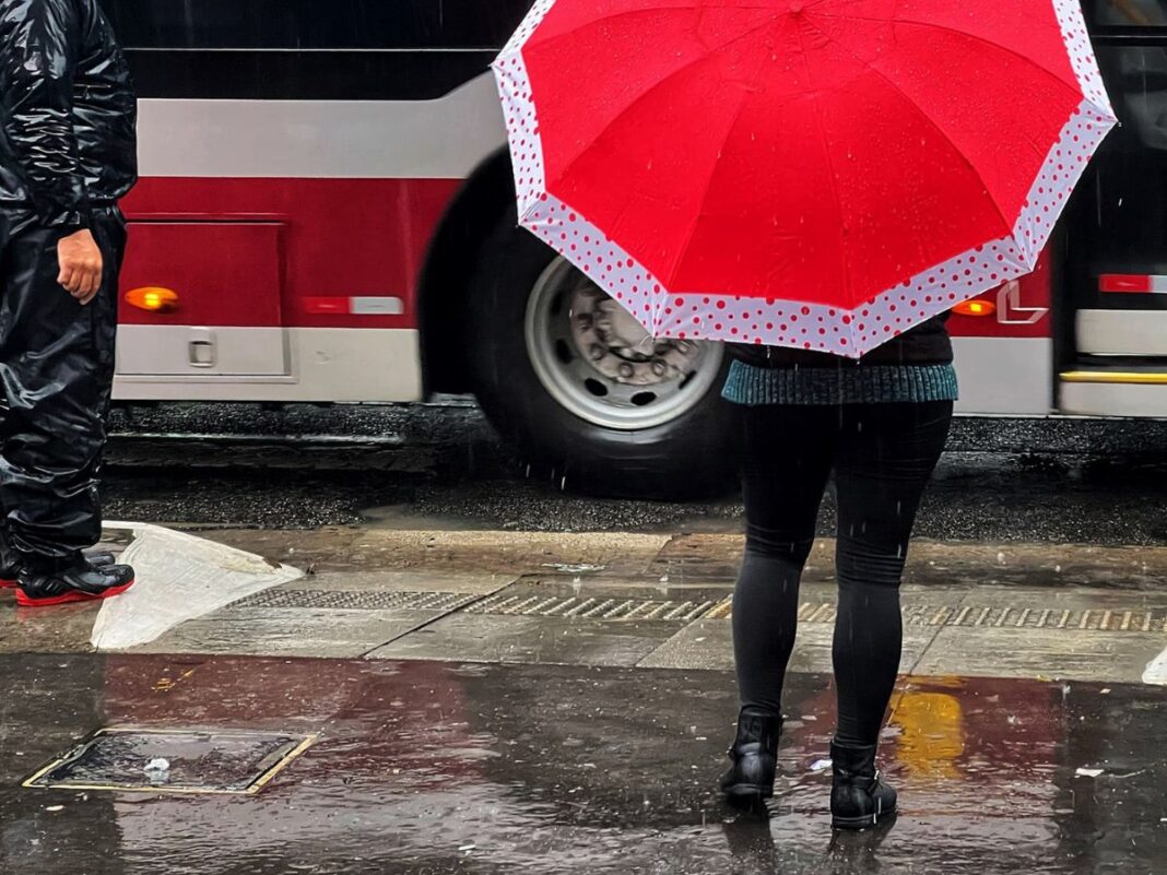 Pessoas andando na Avenida Paulista com guarda-chuva durante temporal