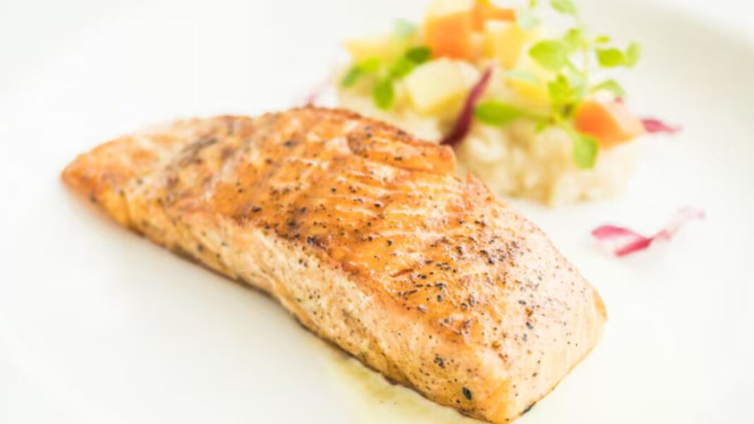 Pedaço de peixe em um prato branco com porção de vinagrete