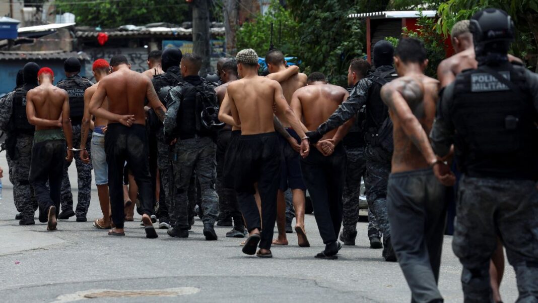 operação rio de janeiro REUTERS Aline Massuca A fotografia, capturada em um ambiente de rua, numa comunidade, mostra um grupo de homens, alguns deles detidos, sendo conduzidos por policiais militares.