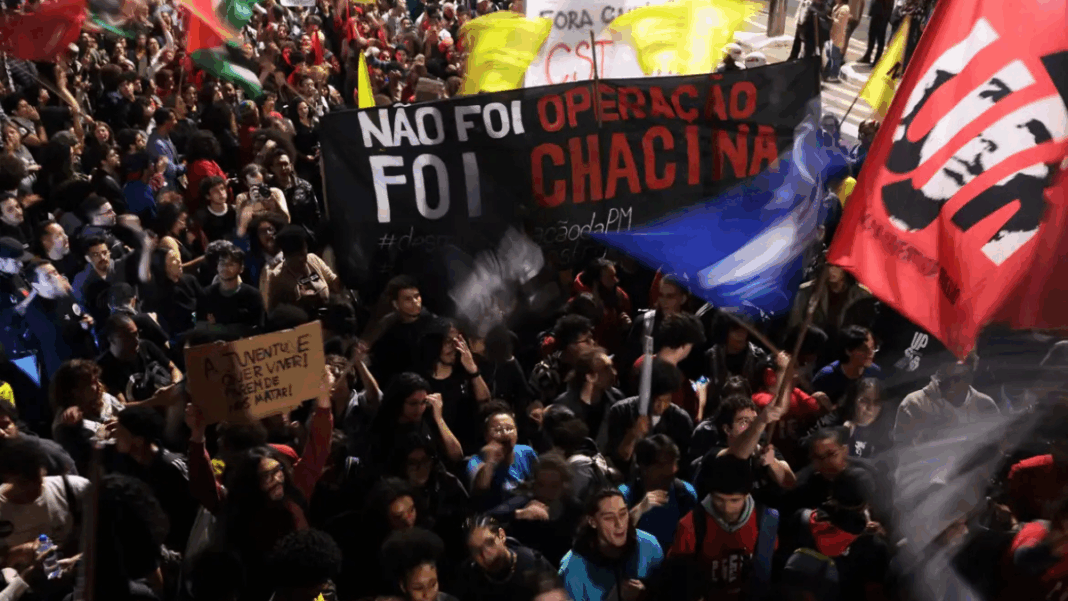 Protestos São Paulo_Rio de Janeiro_Foto_Paulo Pinto_Agência Brasil Multidão participa de manifestação à noite segurando faixas e cartazes. Um dos principais cartazes diz “Não foi operação, foi chacina”, e outro, “A juventude quer viver! Parem de nos matar!”. Bandeiras coloridas são erguidas entre os manifestantes.
